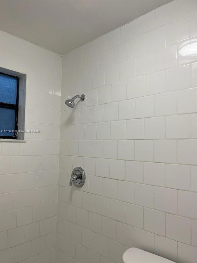 bathroom featuring a tile shower and toilet