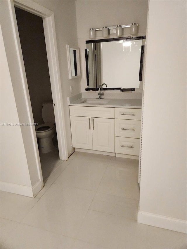 bathroom featuring toilet, baseboards, vanity, and tile patterned floors