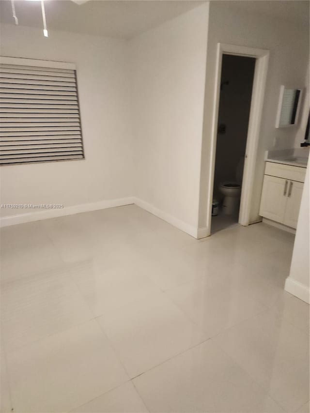 unfurnished room with light tile patterned flooring and baseboards