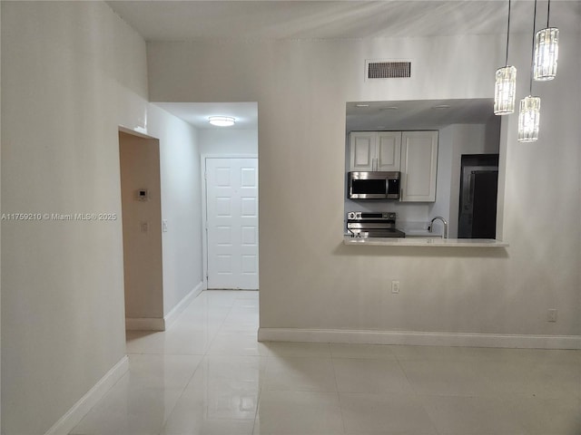 kitchen featuring baseboards, visible vents, appliances with stainless steel finishes, a sink, and light tile patterned flooring