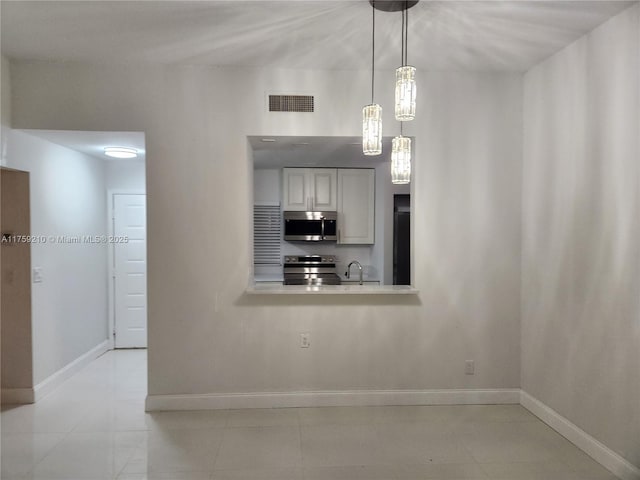 unfurnished dining area featuring visible vents, a sink, baseboards, and light tile patterned flooring