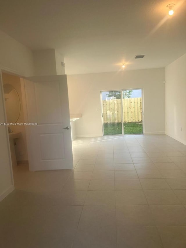 unfurnished room featuring tile patterned flooring, visible vents, and baseboards