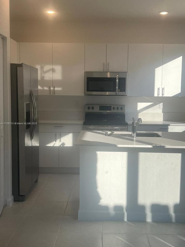 kitchen featuring stainless steel appliances, light countertops, a sink, and light tile patterned floors