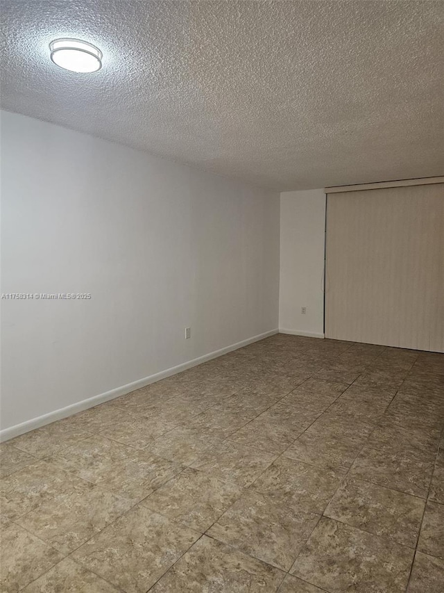 empty room featuring a textured ceiling and baseboards