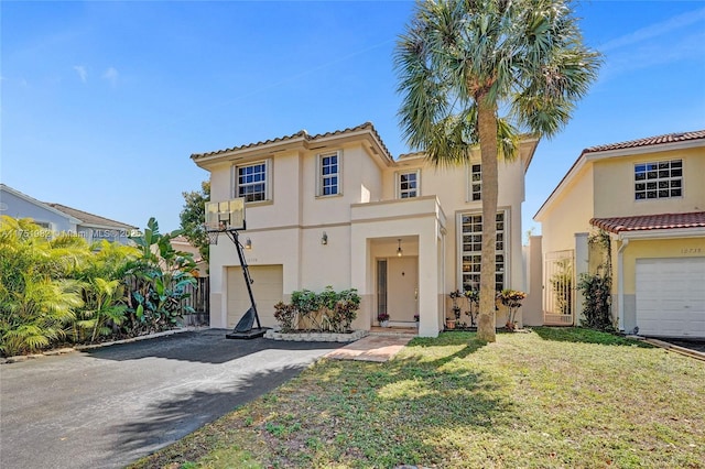 mediterranean / spanish home with a garage, aphalt driveway, a front lawn, and stucco siding