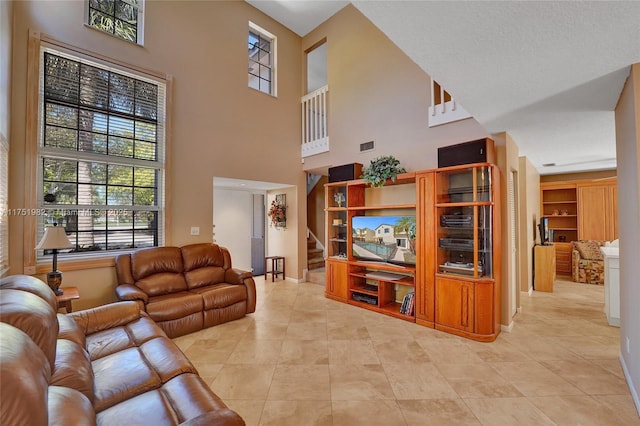 living room with light tile patterned floors, visible vents, stairway, a high ceiling, and baseboards