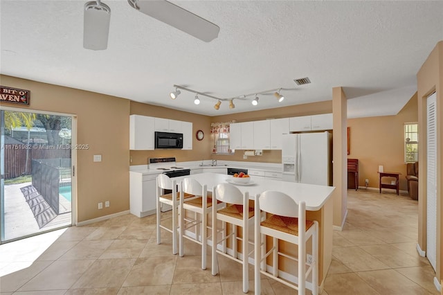 kitchen featuring white refrigerator with ice dispenser, light countertops, range with electric stovetop, and black microwave