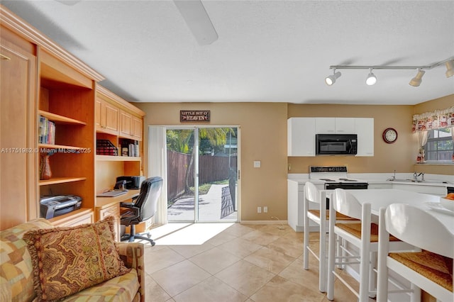 interior space with black microwave, a textured ceiling, range with electric stovetop, light countertops, and built in study area