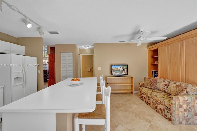 kitchen with a breakfast bar, a center island, white refrigerator with ice dispenser, visible vents, and light countertops