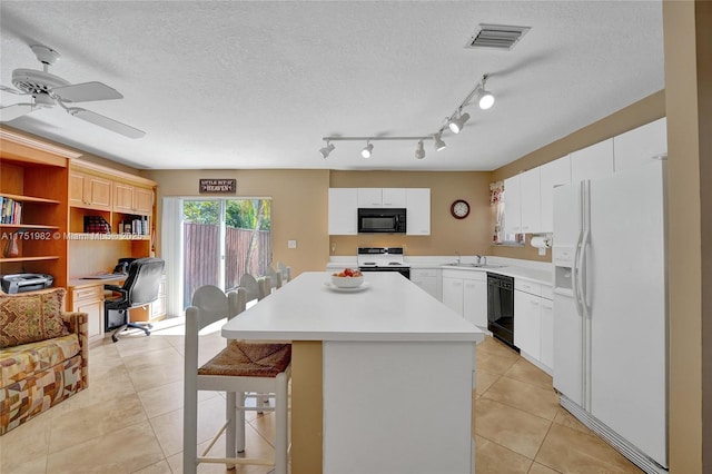 kitchen featuring light tile patterned floors, a sink, visible vents, light countertops, and black appliances