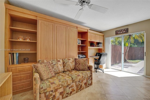 living area with a ceiling fan, built in study area, a textured ceiling, and light tile patterned flooring