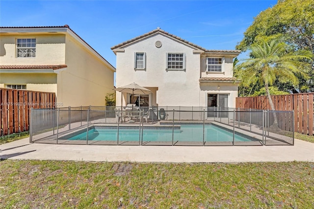 back of house with a fenced in pool, a fenced backyard, a patio, and stucco siding