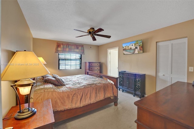 carpeted bedroom with a textured ceiling, a closet, and a ceiling fan