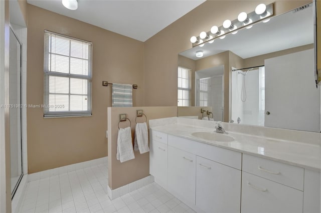 full bath featuring tile patterned flooring, baseboards, a shower, and vanity