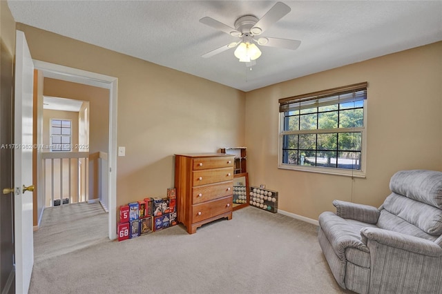 sitting room featuring carpet, visible vents, a ceiling fan, a textured ceiling, and baseboards