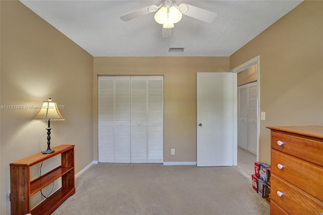 bedroom with a closet, light colored carpet, visible vents, a ceiling fan, and baseboards