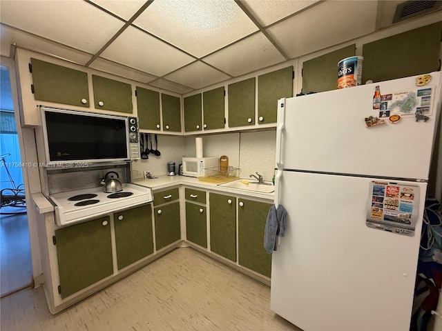 kitchen with white appliances, green cabinets, a sink, and light countertops