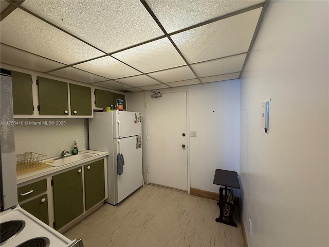 kitchen with a paneled ceiling, light countertops, green cabinets, freestanding refrigerator, and light wood-type flooring