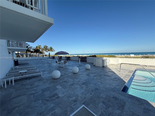 view of patio / terrace featuring a water view, a balcony, and a community pool