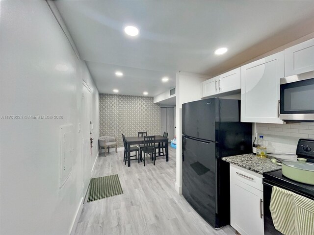 7100 NW 17th St Unit 111, Plantation, FL 33313 - kitchen featuring black appliances, baseboards, white cabinets, wallpapered walls, and light wood-style flooring