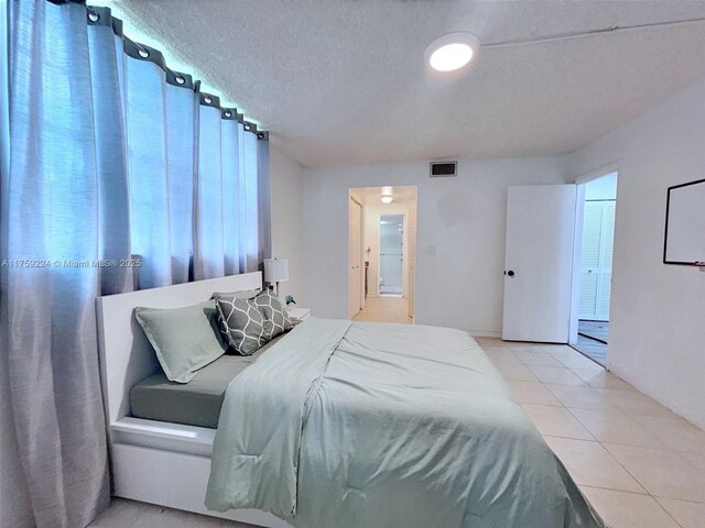 7100 NW 17th St Unit 111, Plantation, FL 33313 - bedroom with tile patterned flooring, a textured ceiling, and ensuite bath