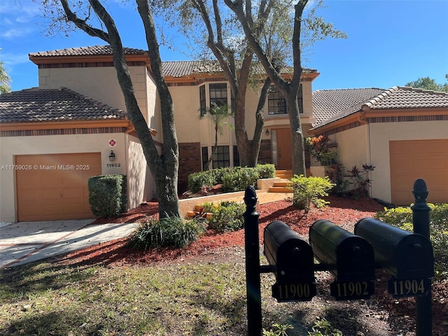 mediterranean / spanish house featuring an attached garage, stucco siding, and a tiled roof