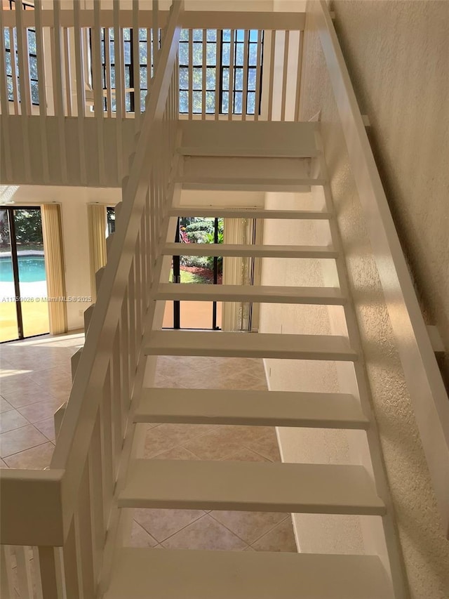 stairway featuring a textured wall, a high ceiling, and tile patterned floors