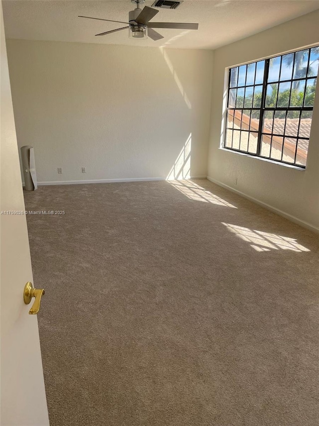 carpeted spare room featuring visible vents, a textured ceiling, a ceiling fan, and baseboards