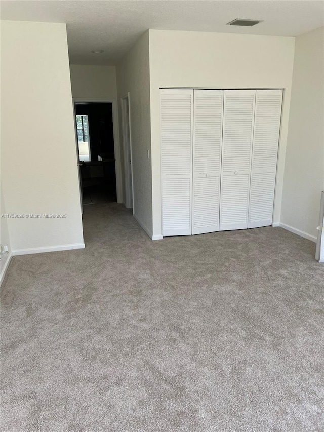 unfurnished bedroom featuring a closet, carpet flooring, visible vents, and baseboards