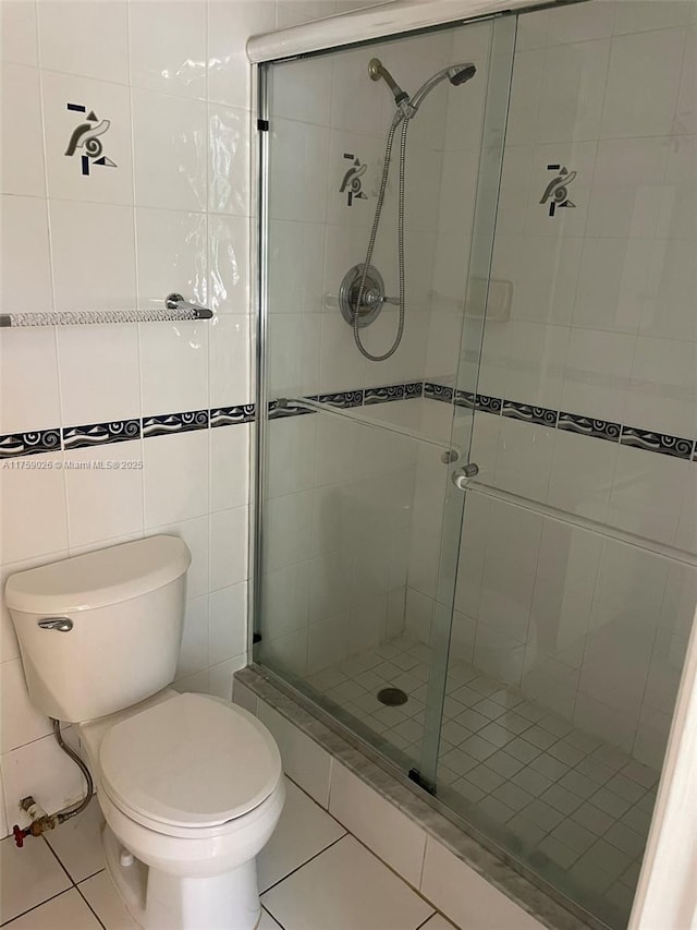 bathroom with a stall shower, tile patterned flooring, tile walls, and toilet