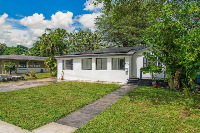 single story home with stucco siding, a front yard, and roof mounted solar panels