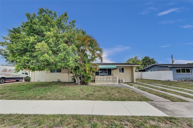 ranch-style home with a front yard, fence, and stucco siding