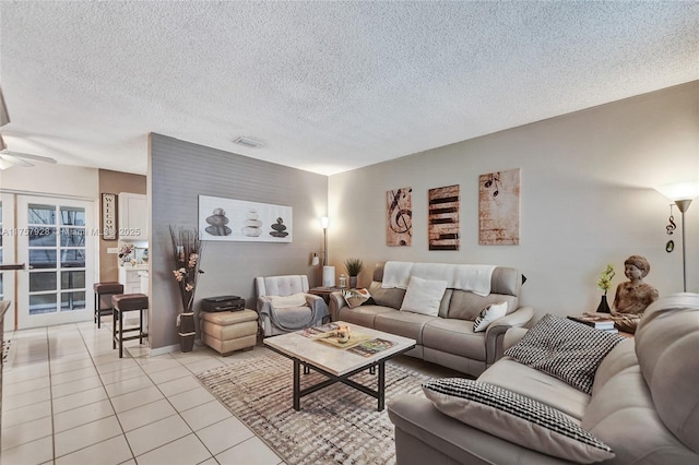 living area featuring light tile patterned floors, a textured ceiling, visible vents, and a ceiling fan