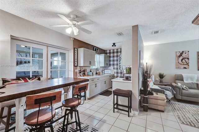 kitchen with light countertops, open floor plan, visible vents, and white microwave