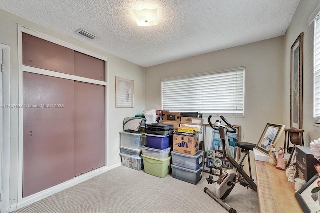 workout room with a textured ceiling, carpet, and visible vents