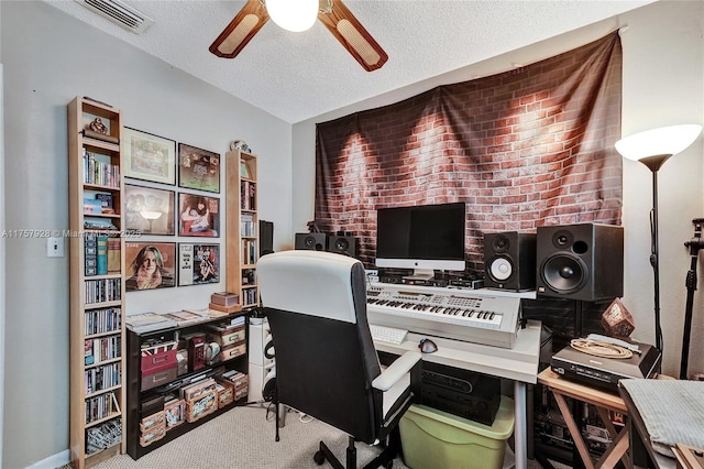 carpeted home office featuring a textured ceiling, visible vents, and a ceiling fan