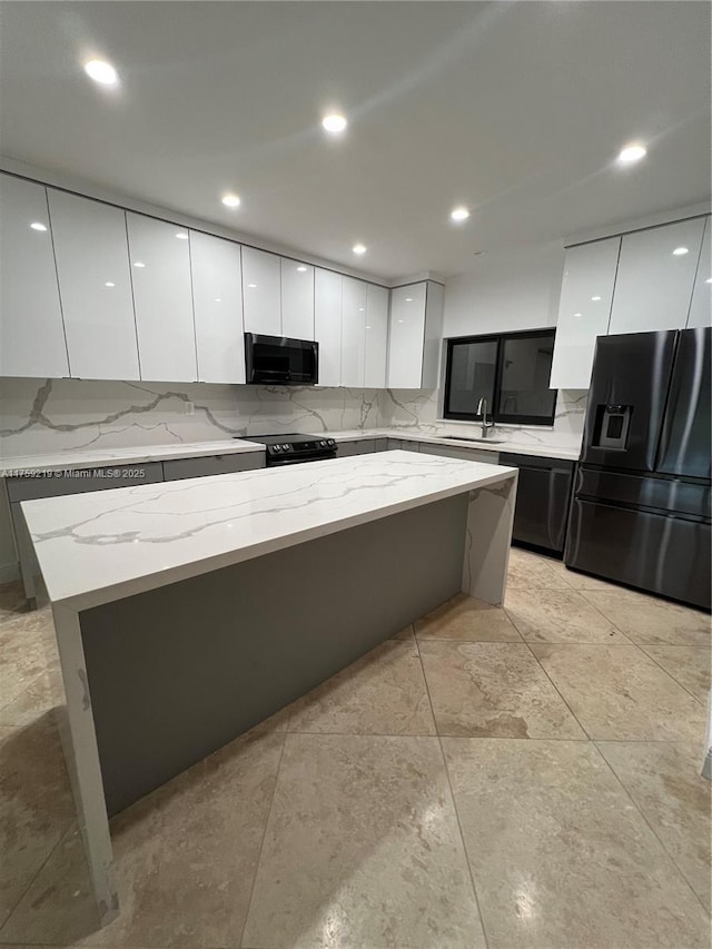 kitchen featuring black appliances, modern cabinets, a sink, and white cabinetry