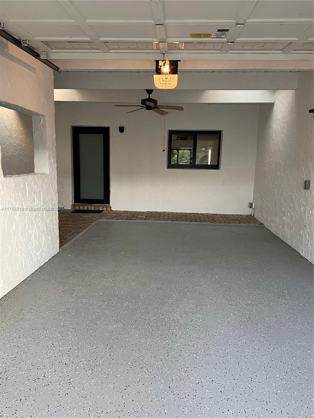 garage featuring a textured wall, a ceiling fan, and a garage door opener