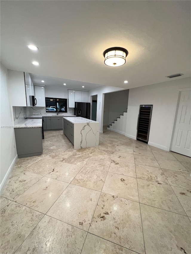 kitchen featuring recessed lighting, visible vents, baseboards, a center island, and black refrigerator with ice dispenser