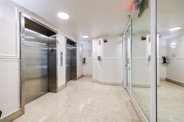 corridor featuring elevator and baseboards