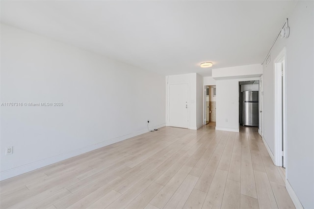 spare room featuring light wood-type flooring and baseboards