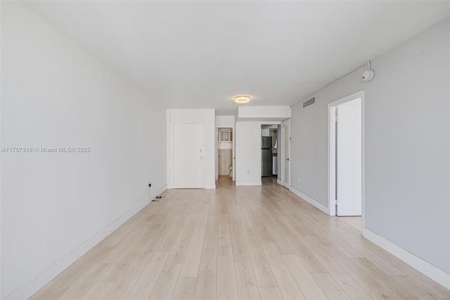 empty room with light wood-style flooring, visible vents, and baseboards