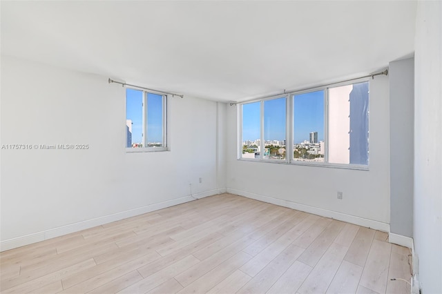 empty room featuring a view of city, baseboards, and wood finished floors