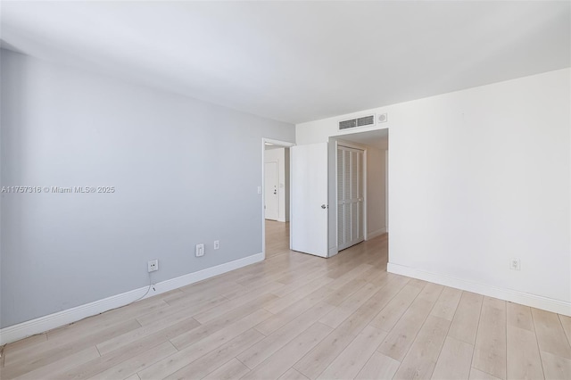 unfurnished room with light wood-type flooring, visible vents, and baseboards