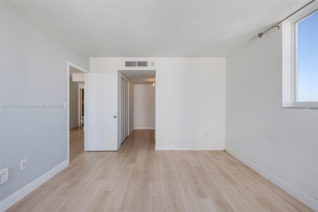 unfurnished room with light wood finished floors, baseboards, and visible vents