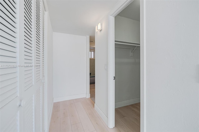 corridor featuring light wood-style flooring and baseboards