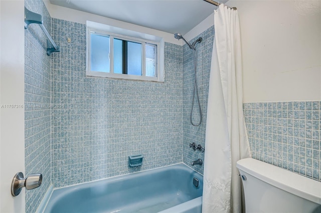 bathroom with tile walls, toilet, and shower / bath combo with shower curtain