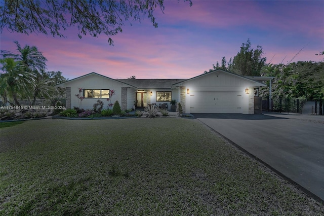 ranch-style home featuring a garage, driveway, fence, and a front yard