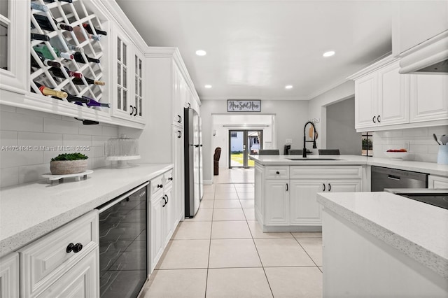 kitchen featuring light tile patterned floors, wine cooler, stainless steel appliances, white cabinetry, and a sink