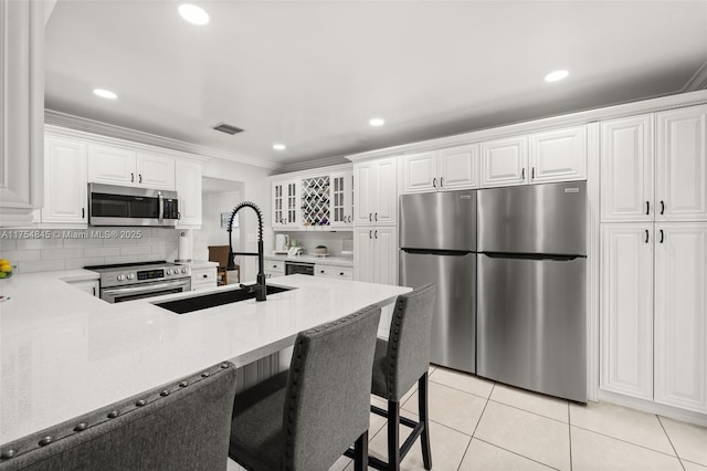 kitchen with light tile patterned floors, visible vents, backsplash, appliances with stainless steel finishes, and a sink